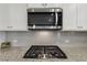 A stainless steel microwave sits above a gas cooktop with a granite countertop and white cabinets at 3878 Amicus Dr, Buford, GA 30519