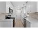 Galley kitchen featuring white cabinets, stainless steel appliances, and light stone backsplash at 5225 Maple Valley Sw Rd, Mableton, GA 30126