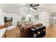 Bright living room with a ceiling fan, cozy seating, and a fireplace with white brick surround at 5785 Woodruff Rd, Chattahoochee Hills, GA 30213