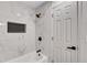 The bright white bathroom features a soaking tub, black fixtures, and marble-style tile at 3632 Glen Mora Drive, Decatur, GA 30032