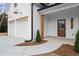 A stylish front entrance with dual garage doors, a covered porch, and a well-manicured lawn at 5010 Hyde Way, Cumming, GA 30040