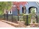 A black metal fence borders a yard and blue home with shrubbery, brick walkway, and colorful tree at 1040 Amsterdam Ne Ave, Atlanta, GA 30306