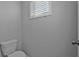 Clean, neutral powder room with toilet and single window at 2650 Longacre Park Way, Lawrenceville, GA 30044