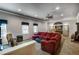 Open living room with plush red sectional, carpeted flooring, bright windows, and arched doorway at 172 Knightwood Point, Acworth, GA 30101