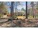 View of a multi-level backyard with a large deck and patio, surrounded by lush greenery and tall trees at 2504 Loch View Sw Ct, Conyers, GA 30094