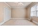 Neutral bedroom featuring a ceiling fan, large window with blinds, and a double-door closet at 2504 Loch View Sw Ct, Conyers, GA 30094