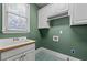 Bright laundry room with a utility sink, green walls, and ample cabinet storage at 2504 Loch View Sw Ct, Conyers, GA 30094