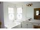 Well-lit bathroom with a corner tub, dual windows, and a white vanity with decorative accents at 179 Hunters Crk, Dallas, GA 30157