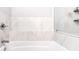 Close-up on bathroom tub with marble surround and a glass-enclosed shower at 390 17Th Nw St # 5031, Atlanta, GA 30363