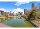 A calm pond reflects modern buildings and trees under a partly cloudy sky, offering a serene view at 390 17Th Nw St # 5031, Atlanta, GA 30363