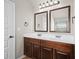 This bathroom has a long vanity with dual sinks, dark-wood cabinets, and two decorative mirrors at 1645 Renfroe Run, Cumming, GA 30041