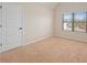 This bedroom is brightly lit from the window and features neutral carpet and white doors and trim at 1645 Renfroe Run, Cumming, GA 30041