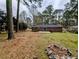A spacious backyard featuring a brick home, green grass, tall trees and a fire pit at 4430 Locksley Rd, Tucker, GA 30084