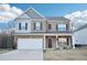 Charming two-story brick home with a covered porch and attached two-car garage on a sunny day at 939 Brittfield Way, Loganville, GA 30052