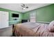 Bedroom featuring a TV, ceiling fan, window, and green walls with white trim at 100 Cowan Trl, Stockbridge, GA 30281