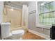 A bathroom showcasing a toilet and bathtub with a shower, next to a window at 3020 Harold Se Ave, Atlanta, GA 30316