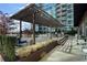 Chic rooftop patio offers comfortable seating and dining areas under a pergola, surrounded by manicured landscaping at 923 Peachtree Ne St # 930, Atlanta, GA 30309
