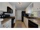Galley kitchen boasts white cabinets, granite countertops, and modern black appliances at 633 N Fairfield Dr, Peachtree City, GA 30269