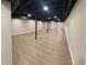 Finished basement with black ceiling, wood-look flooring, and supporting columns at 1027 Goza Rd, Fayetteville, GA 30215