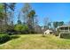 A spacious backyard with mature trees, lush lawn, a deck, and a detached garage offers privacy and space at 115 Heritage Cir, Mcdonough, GA 30253