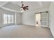 Large bedroom with tray ceilings, a ceiling fan, plush carpet, and access to the bathroom at 3550 Gravitt Rd, Cumming, GA 30040