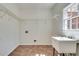 Laundry room with a utility sink, tile floor, and a window for natural light at 3550 Gravitt Rd, Cumming, GA 30040
