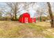 Quaint backyard featuring a red barn-style storage building with white trim and double doors at 2852 Crabapple Lane, Dacula, GA 30019