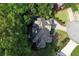 An aerial view of a landscaped yard and driveway leading up to a house with dark roof nestled among lush green trees at 4441 Langdon Se Walk, Smyrna, GA 30080
