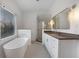 Modern bathroom featuring white cabinetry, a soaking tub, glass enclosed shower, and natural light at 1025 Abingdon Ln, Johns Creek, GA 30022