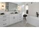 Bathroom featuring a modern vanity with black hardware, sconces, tub, and large window at 1025 Abingdon Ln, Johns Creek, GA 30022