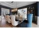 Elegant dining room boasts a stylish light fixture, dark accent wall, and views to the entry staircase at 1025 Abingdon Ln, Johns Creek, GA 30022
