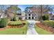 Stunning two-story home featuring a manicured lawn, lush landscaping, and a long driveway, all surrounded by mature trees at 1025 Abingdon Ln, Johns Creek, GA 30022