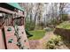 Backyard view of a green playground with a climbing wall surrounded by natural landscaping at 1025 Abingdon Ln, Johns Creek, GA 30022