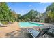 Community pool surrounded by lush greenery, chaise lounges and umbrellas for shade at 925 Seasons Pkwy, Norcross, GA 30093