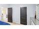 Bedroom featuring two paneled wooden doors, gray walls, and a glimpse into an adjacent room at 2248 Newbury Oaks Dr, Lawrenceville, GA 30044