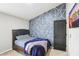 Inviting bedroom featuring a bed with blue covers and a geometric designed accent wall at 2248 Newbury Oaks Dr, Lawrenceville, GA 30044
