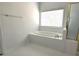 Bathroom featuring a soaking tub with gold fixtures, white tile, and a window at 3070 Ridge Oak Dr, Suwanee, GA 30024