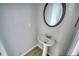 Powder room featuring wood-look floors, pedestal sink, and a round mirror at 690 Park Place Way, Social Circle, GA 30025