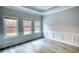 Bright bedroom featuring neutral paint, wood-look floors, large windows, and tray ceiling at 690 Park Place Way, Social Circle, GA 30025