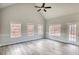 Living room with wood-look floors, large windows, and an access door to the backyard at 690 Park Place Way, Social Circle, GA 30025