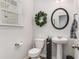 Charming powder room with a pedestal sink, round mirror, and a decorative wreath on the wall at 224 Shoals Bridge Rd, Acworth, GA 30102