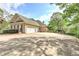 Long driveway and three-car garage, surrounded by lush greenery and mature trees in a serene setting at 8155 Legends View Ct, Cumming, GA 30028