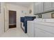 This well-lit laundry room features a dog wash station, tile flooring, and appliances at 8155 Legends View Ct, Cumming, GA 30028