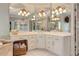 Bright main bathroom features white cabinets, white tile floors, mirrors, and a crystal chandelier at 8155 Legends View Ct, Cumming, GA 30028