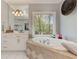 Bright main bathroom features white cabinets, a large window with trees, and a tub with beige diamond pattern at 8155 Legends View Ct, Cumming, GA 30028
