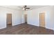 A spacious bedroom with dark hardwood floors, multiple doorways, a ceiling fan, and neutral walls at 161 Basil St, Cumming, GA 30040