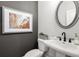 Chic powder room featuring a pedestal sink, round mirror, and elegant decor at 733 Stickley Oak Way, Woodstock, GA 30189