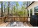 Relax on this back deck with wooded views, featuring black metal table and chairs plus a gas grill at 3560 Chattahoochee Rd, Cumming, GA 30041