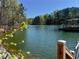 Beautiful lake view with a private covered dock and lush green trees under a clear blue sky at 3560 Chattahoochee Rd, Cumming, GA 30041
