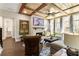 Cozy living room with wood-beamed ceiling, brick fireplace, and large windows showcasing outdoor views at 3560 Chattahoochee Rd, Cumming, GA 30041